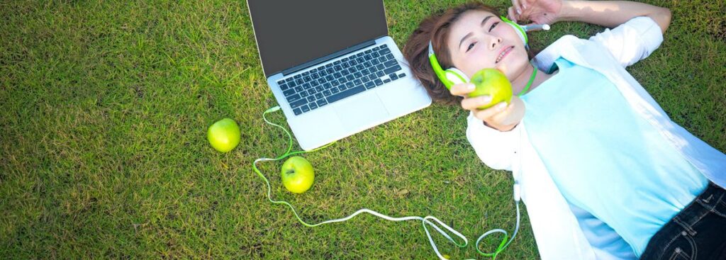 child laying on artificial grass with laptop