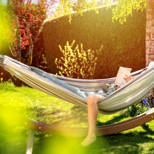 someone laying in hammock reading a book and relaxing