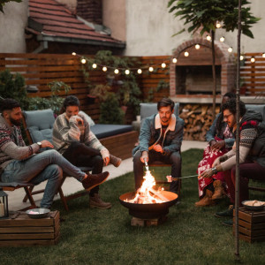 Friends using a fire pit in a garden