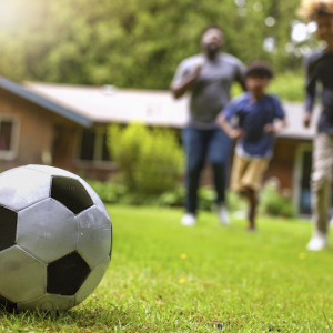 Family playing football on artificial grass