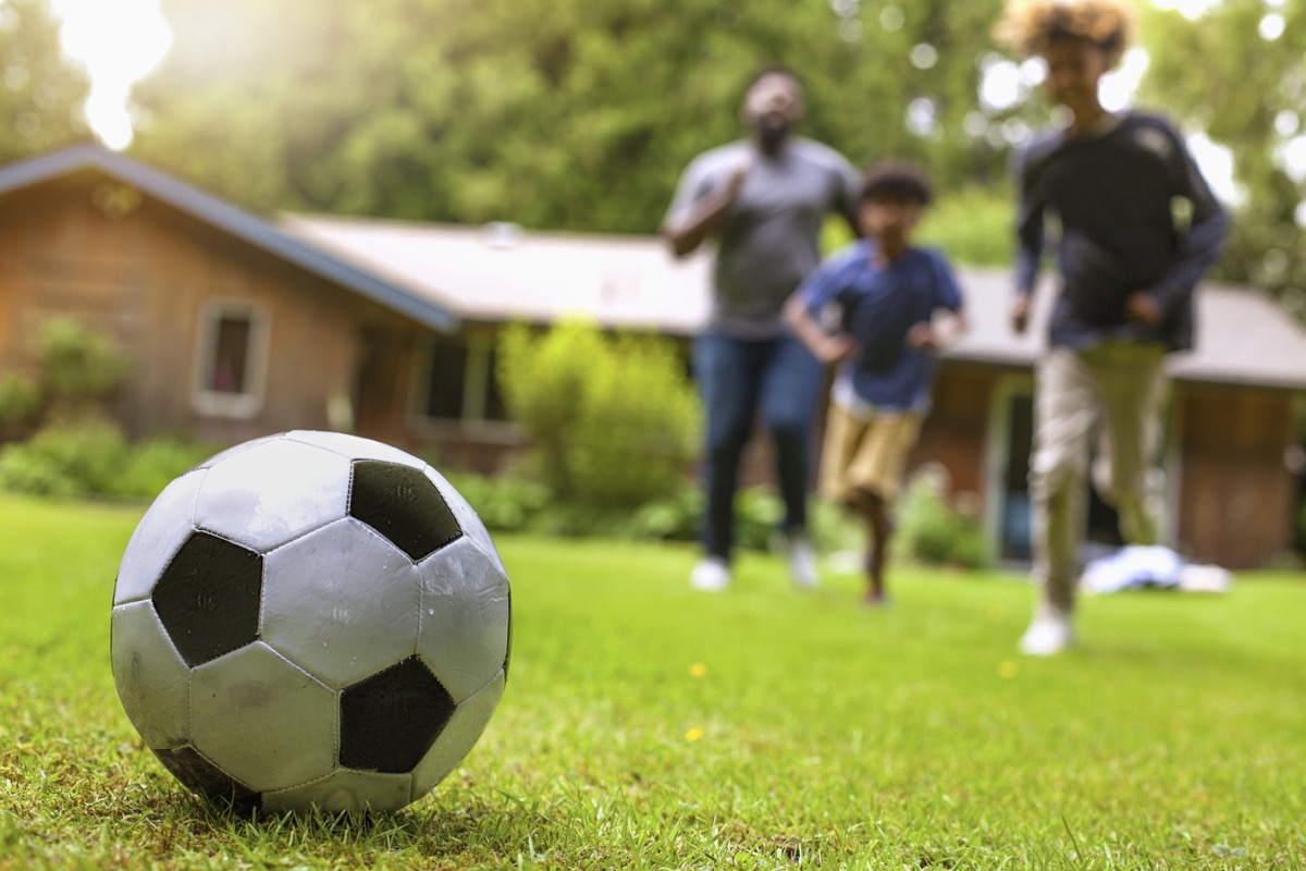 Family playing football on artificial grass